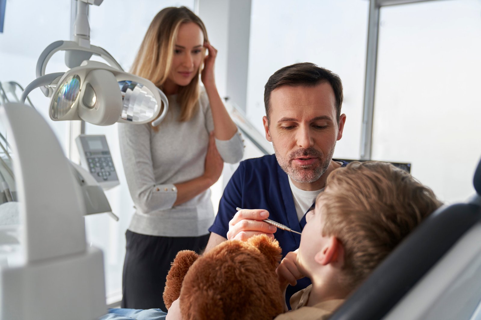 Little boy having visit at dentist's office with mother